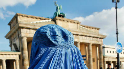 Kvinna iklädd burka vid Brandenburger Tor i Berlin.