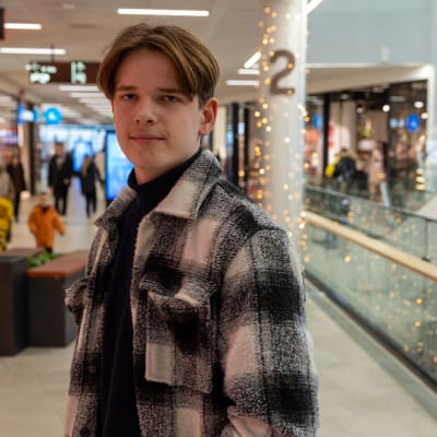 Otso Rovio katsoo kameraan. Taustalla näkyy kauppakeskuksen käytävää ja portaikkoa.