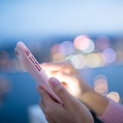 Händer håller i en mobiltelefon