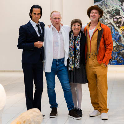 Nick Cave, Thomas Houseago och Brad Pitt tillsammans med en fjärde person, en anhörig till Houseago, på Sara Hildéns konstmuseum. De står och håller om varandra och och omkring dem skymtar skulpturer och på väggen bakom dem en målning.
