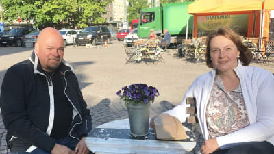 Ett leende par på uteservering på Tölö torg.