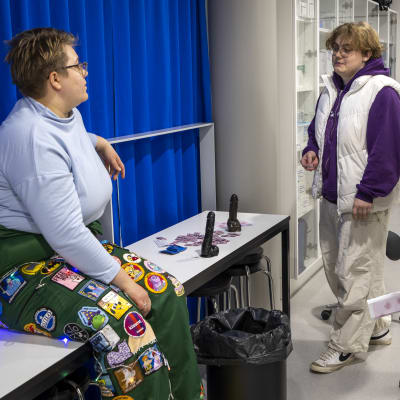 Kätilöopiskelija Aura Rissanen opettaa lukiolaisille kondomin käyttöä, Filip Koivisto kavereineen kuuntelee.