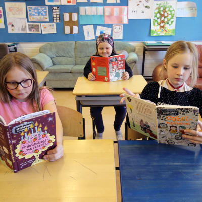 Aada Johansson, Peppi Johansson och Maya Ikonen sitter och läser i sitt klassrum i Svenska skolan i Varkaus.