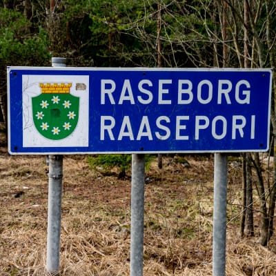 En skylt, där det står Raseborg, står i terrängen vid kommungränsen.