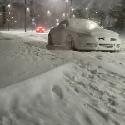 Gatuvy från Eirastranden i södra Helsingfors under snöstormen Valtteri 29.1.2022. Det finns snö på marken, på en bil och i luften.
