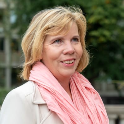 Justitieminister Anna-Maja Henriksson intervjuas. Hon är iklädd en rosa skarf och ljus jacka. 