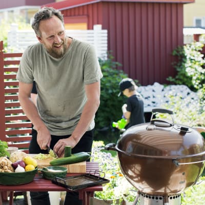 Anders Samuelsson utomhus i solen framför ett bord med fräsha grönsaker och rotsaker.