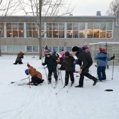 Ekaluokkalaiset hiihtotunnilla opettajansa kanssa.