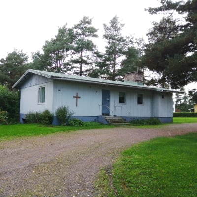 Ett blått hus med kors på väggen som är Ingå församlings ungdomshus.