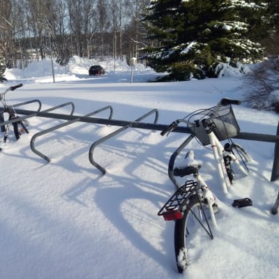 Pyöräteline ja pari fillaria lumihangessa.