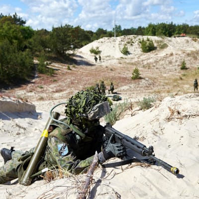 sotilas rynnäkkökivääreineen hiekkadyynillä