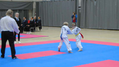 Två unga idrottare går en match i taekwondo.