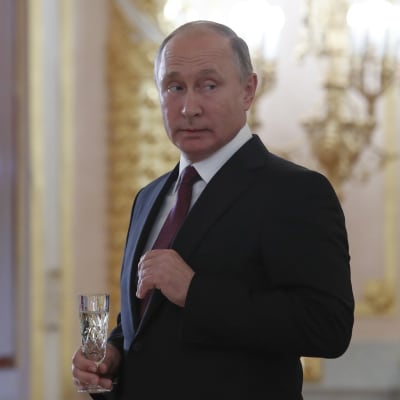 Vladimir Putin sr sig över axeln, klädd i kostym med ett champagneglas i handen