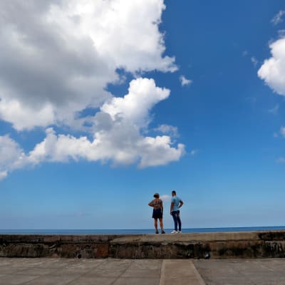 Ett par står på en mur och tittar på havet. 