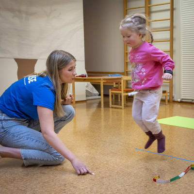 Kolmevuotias Carolina hyppää ja Karoliina Uusitalo mittaa.