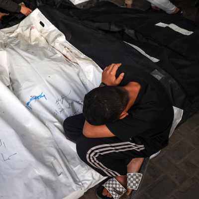 Sörjande pojke i Gaza bredvid insvepta kroppar.