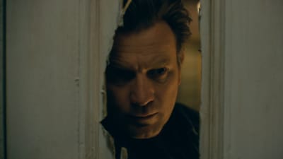 Närbild på Danny (Ewan McGregor) då han tittar in genom ett hål som hackats upp med yxa i en dörr.