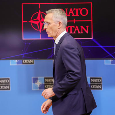 Jens Stoltenberg i profil framför Natos logotyp på en skärm.