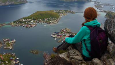 Person sitter och ser ut över en fjord