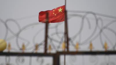 Den kinesiska flaggan över ett internerimgsläger i Xinjiang