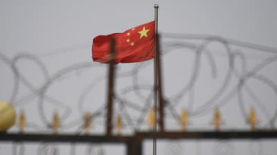 Taggtråd i förgrunden och Kinas flagga i bakgrunden.
