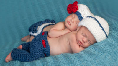 Två bebisar ligger och sover på en filt.