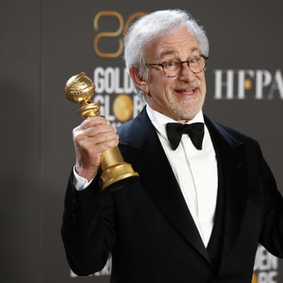 Steven Spielberg i smoking håller upp två guldfärgade statyetter.