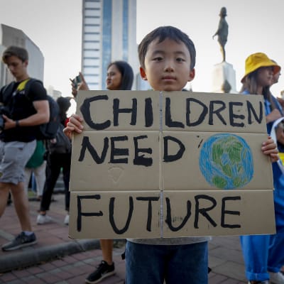 En ung pojke håller i en skylt med texten "Children need future" (barn behöver en framtid) under en klimatstrejk i Bangkok, Thailand i november 2019.