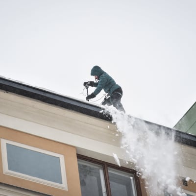 En snöskottare på ett tak i Berghäll i Helsingfors tisdagen den 29.1.2019.