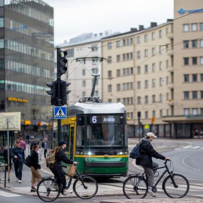 Kaksi pyöräilijää ajaa raitiovaunun editse Sörnäisissä.