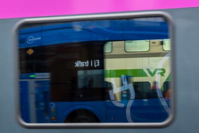 En buss speglas i ett tågfönster.