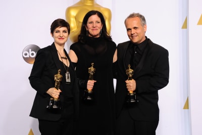 Mathilde Bonnefoy, Laura Poitras och Dirk Wilutzky står bredvid varandra och ser glada ut, de håller alla en Oscarsstatyett i handen.