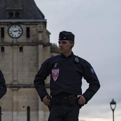 Kaksi poliisia seisoo kirkon edessä. Toinen pitää kädessään rynnäkkökivääriä.