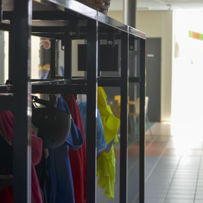 Ytterläder händer på knaggar i en skolkorridor. 
