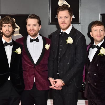Musikgruppen Imagine Dragons poserar för bild klädda i kostym och en vit ros vid bröstet.