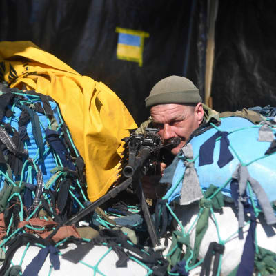 En soldat står i skydd bakom en blå-gul barrikad.