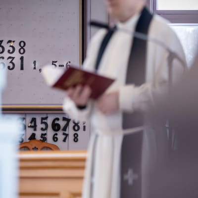 En präst håller i en psalmbok i kyrkan.