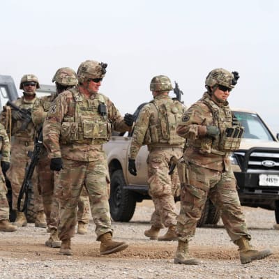 Joukko yhdysvaltalaissotilaita kävelee maastoautojen editse.