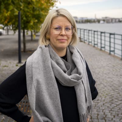 Psykologi Aino Juusola Jätkäsaaressa, taustalla ruskaisia puita ja merta.