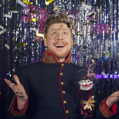 Konfetti faller ner på programledaren Staffan Gräsbeck och kändisreporter Strump-Eva i Strumphittarna 2018.