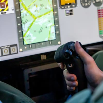 En elev vid kontrollerna i en Hawk-flygsimulator. Närbild av en joystick.