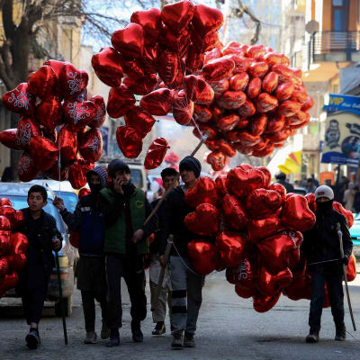 En grupp unga män och pojkar med mängder av röda hjärtformade ballonger.