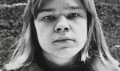 Markus Heikkerö teini-ikäisenä muotokuvassa, jossa hän katsoo läheltä suoraan kameraan. Hänellä on pitkät, suorat hiukset.