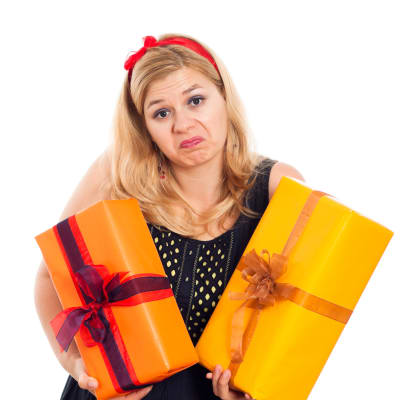 Grimaserande blond kvinna med famnen full av inslagna gåvor