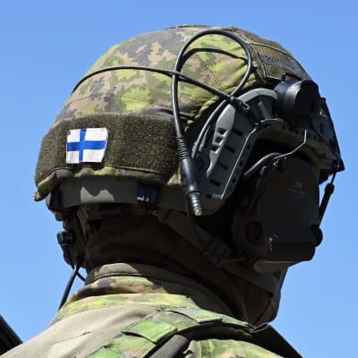 Siniristilippu sotilaan kypärässä.