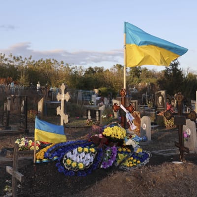 Ukrainan lippuja ja kukkia sotilaan haudalla.