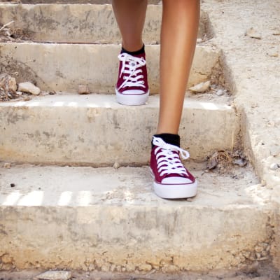 En person med bara ben och röda skor går i en trappa.