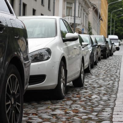En rad av parkerade bilar längs en gata.