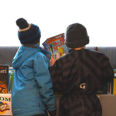 Två pojkar väljer ut serietidningar i Sibbos bokbuss.