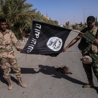 Syrisk militär håller upp en flagga som tillhört Islamiska staten.